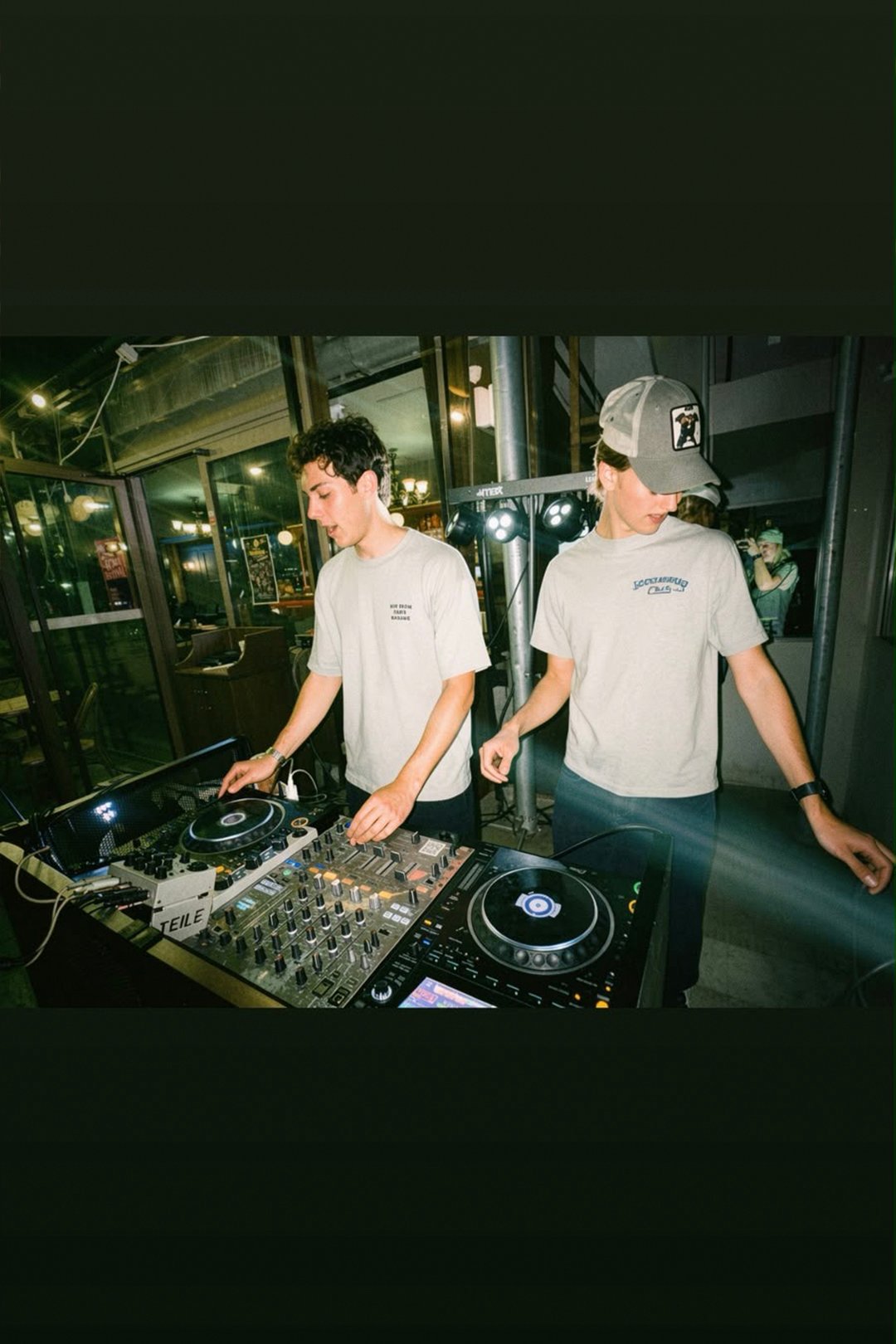 FØR U duo in white T-shirts mixing side by side on a DJ controller at a bar