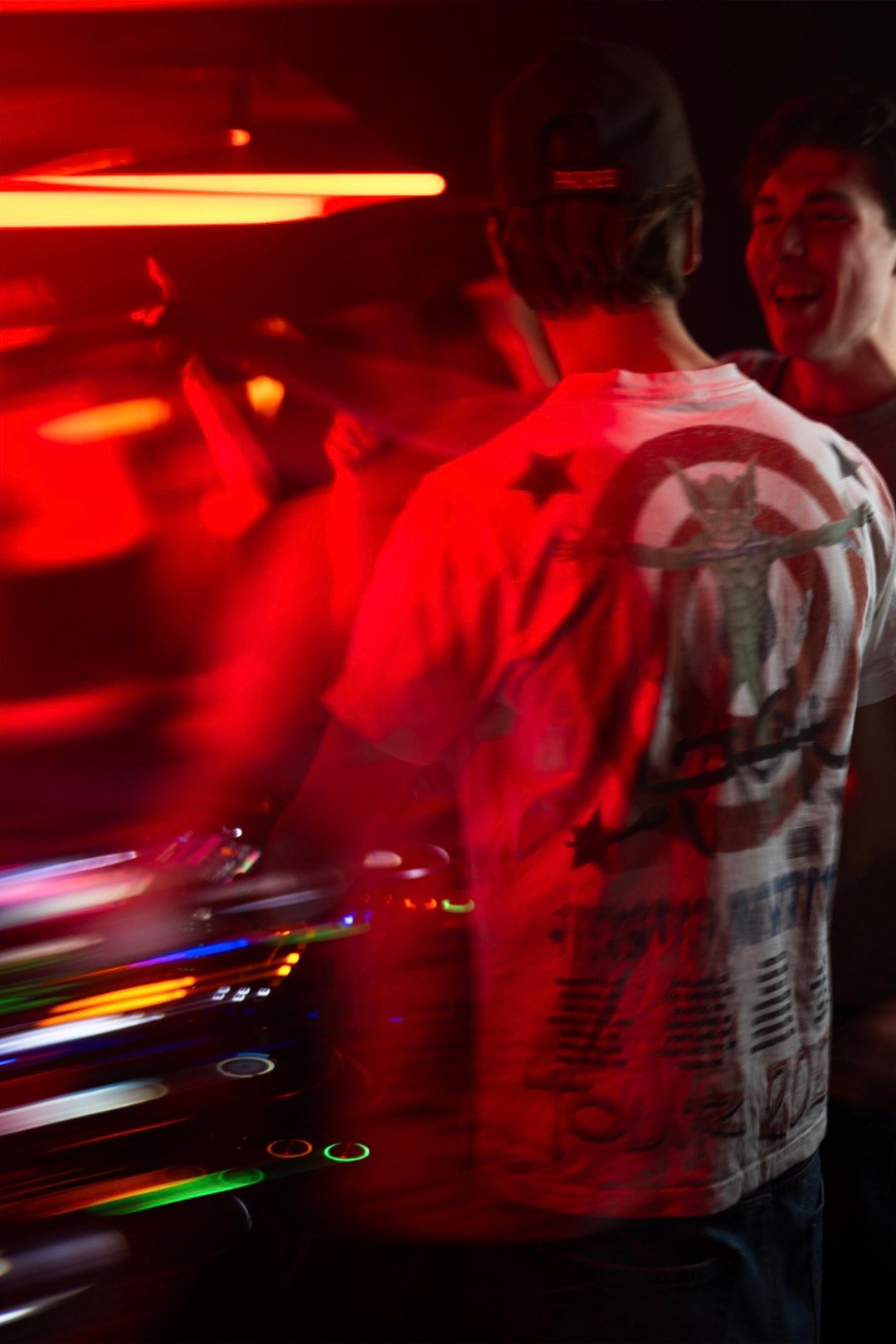 Red-lit motion blur shot of FØR U behind the decks during a club night